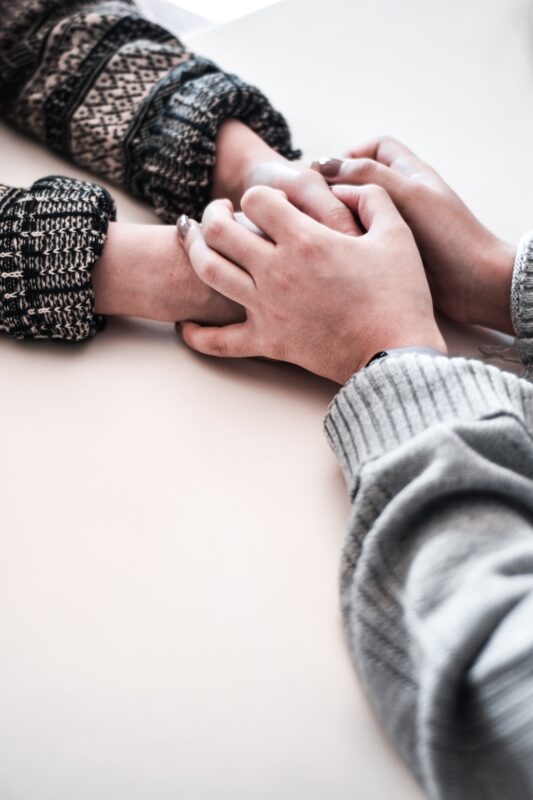 Two women holding each other's hands for support.